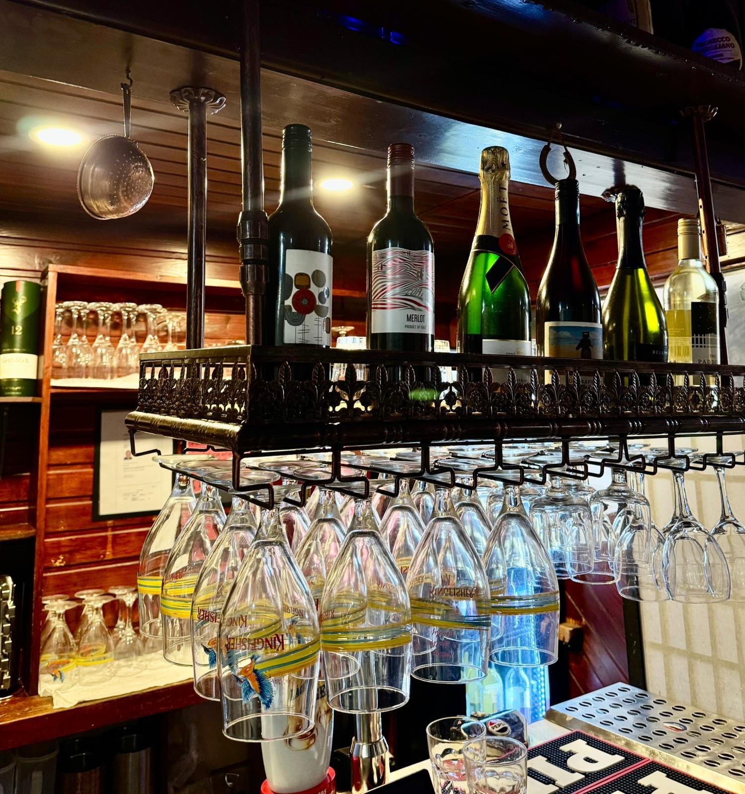 The bar: wine and Moët bottles above a rack of hanging Kingfisher glasses